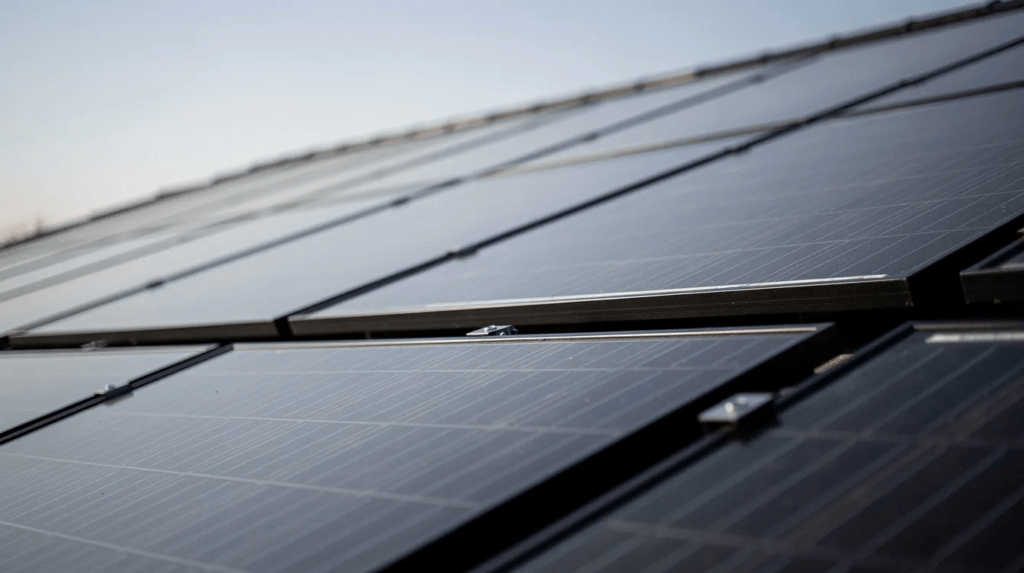 Gros plan sur des panneaux solaires monocristallins noirs, installés sur un toit incliné, illustrant une installation photovoltaïque moderne. Cette image met en avant l'utilisation de l'énergie solaire pour la production d'électricité, soulignant les avantages des panneaux solaires dans le contexte suisse.
